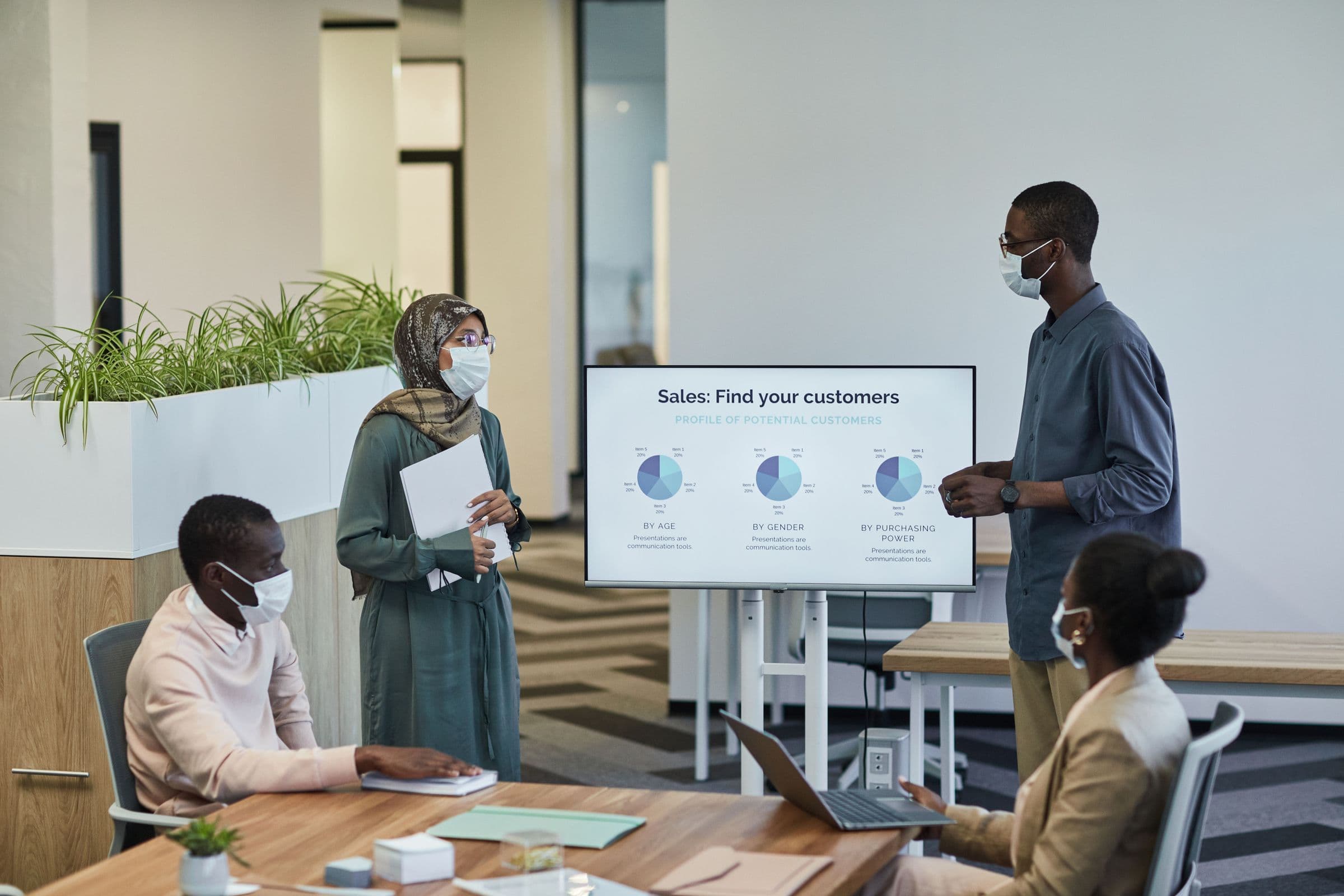 A team reviewing a customer-profile presentation on a screen in a modern office